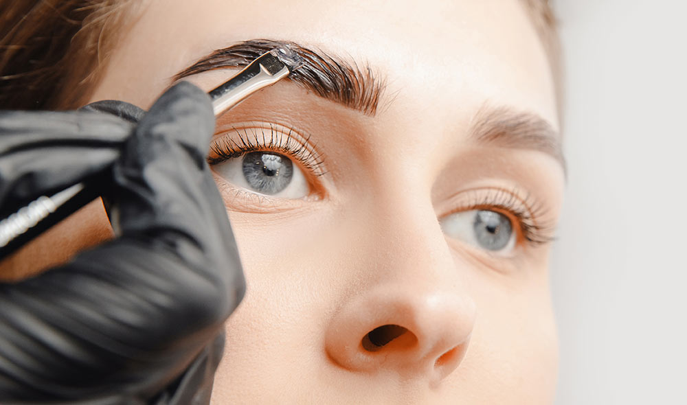 Painting an eyebrow of a woman | Careers Collectiv