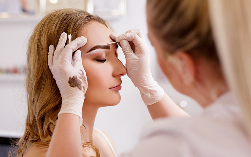 A beautician doing eyebrow filling to her client | Careers Collectiv